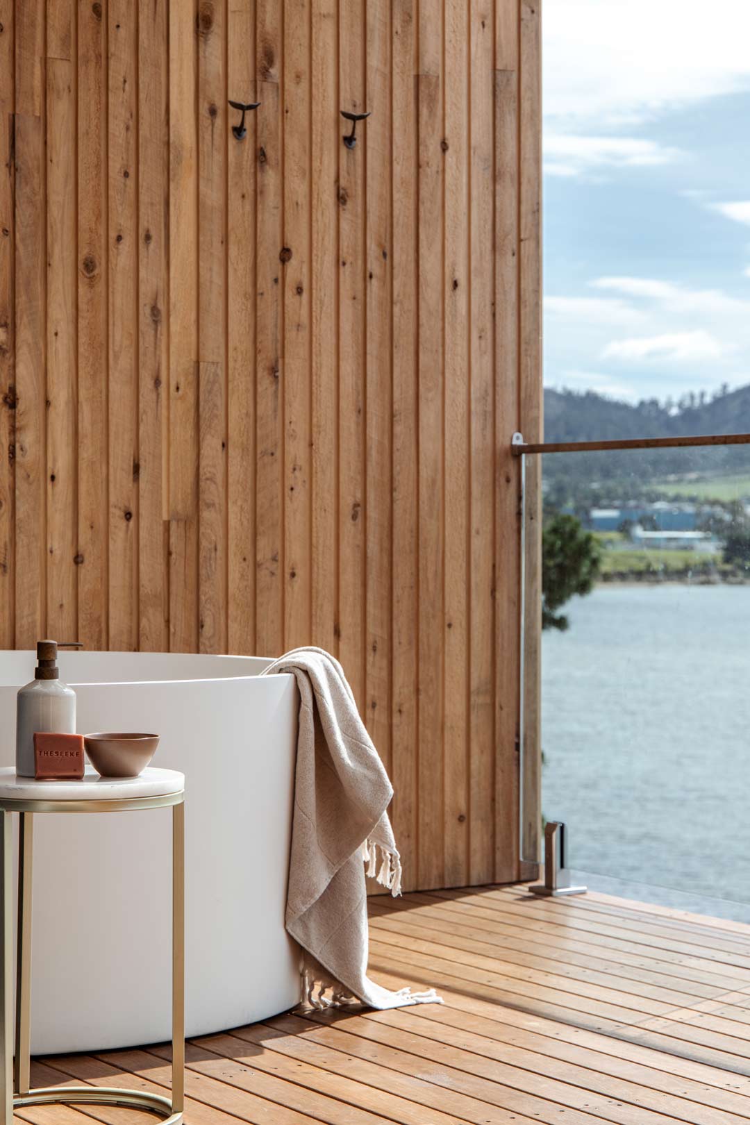 4.-A-luxury-outdoor-bathtub-overlooking-the-water-on-a-timber-panelled-balcony