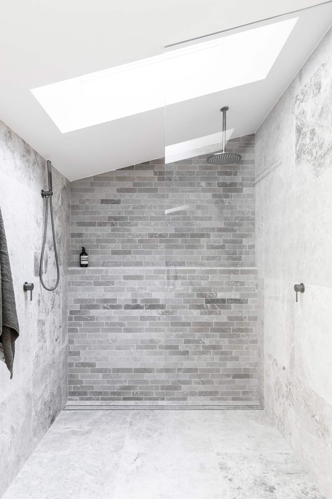 A-Monochromatic-industrial-style-bathroom-with-gunmetal-tapware-grey-subway-tiles-and-a-skylight