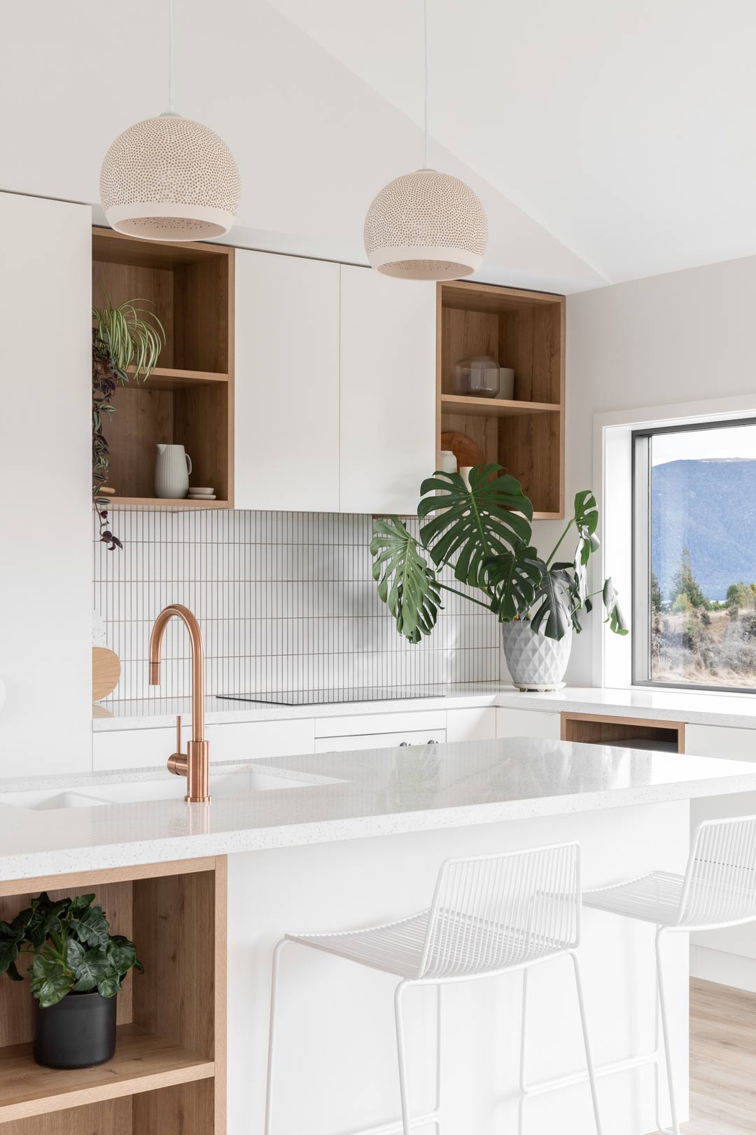 A-bright-airy-kitchen-featuring-copper-tapware-white-cabinetry-and-timber-shelves