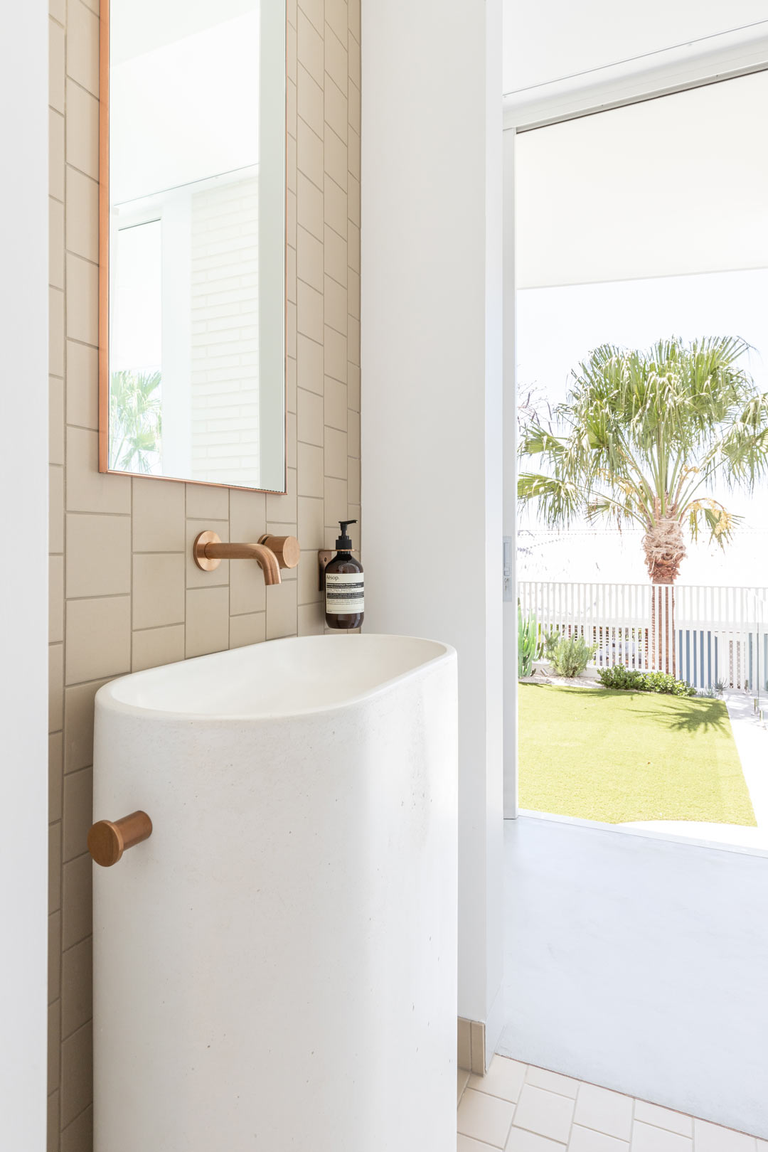 A-bright-airy-powder-room-in-a-modern-Australian-beach-house-with-brushed-copper-tapware-and-a-concrete-pedistal-basin.jpg?format=webp&width=1040