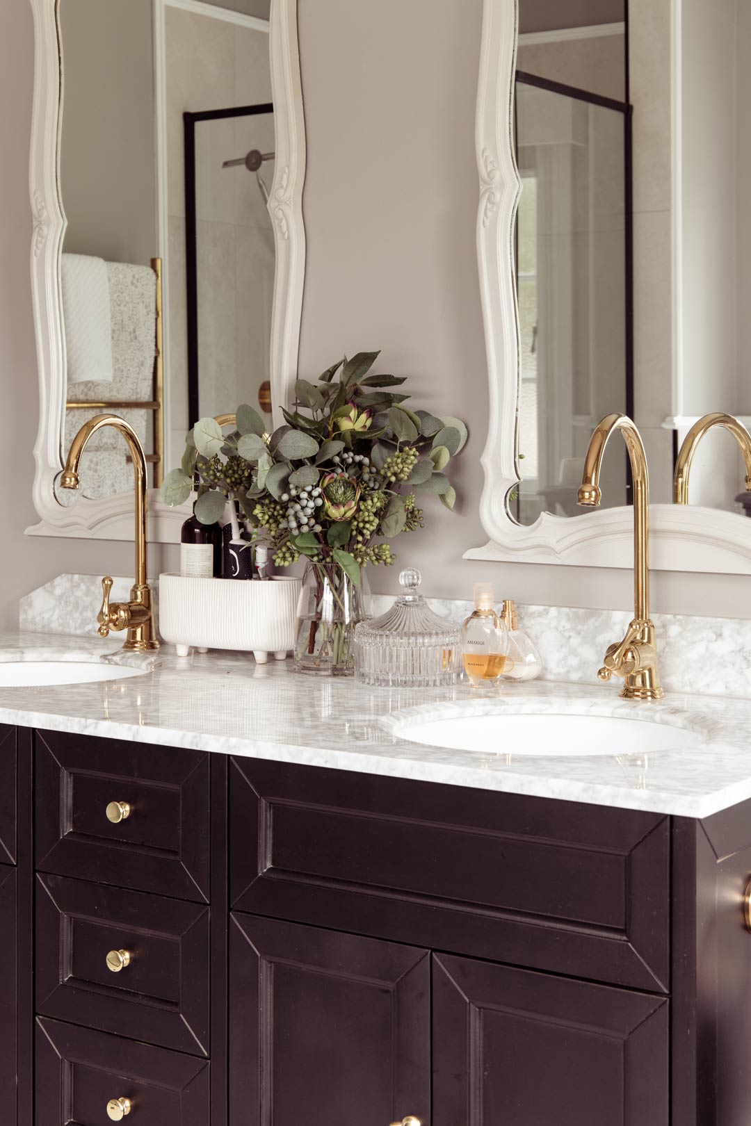 A-dark-solid-timber-vanity-unit-with-a-marble-vanity-top-paired-with-brushed-brass-handles-and-tapware