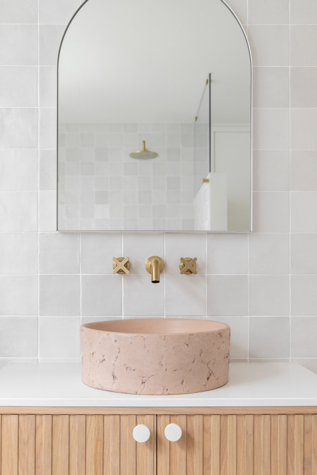 A-light-bright-bathroom-with-brushed-brass-tapware-handmade-neutral-tiles-and-a-concrete-pink-basin