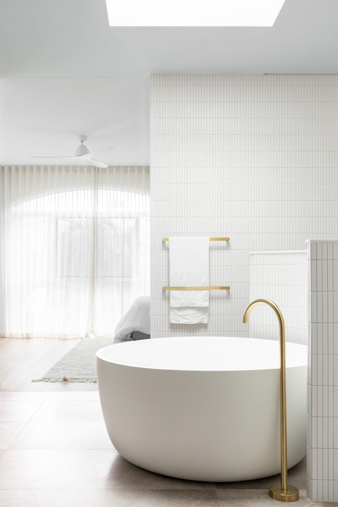 A-neutral-luxurous-ensuite-featuring-brushed-brass-tapware-kit-kat-finger-tiles-and-a-circular-bath