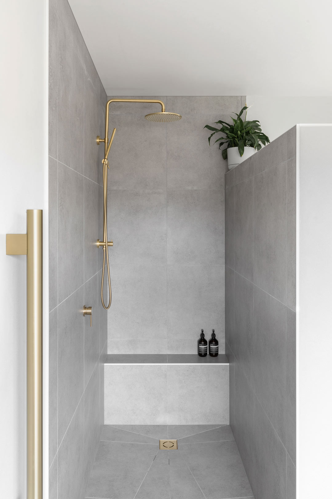 A-simple-bathroom-with-a-neutral-colour-palette-grey-tiles-and-brushed-brass-tapware