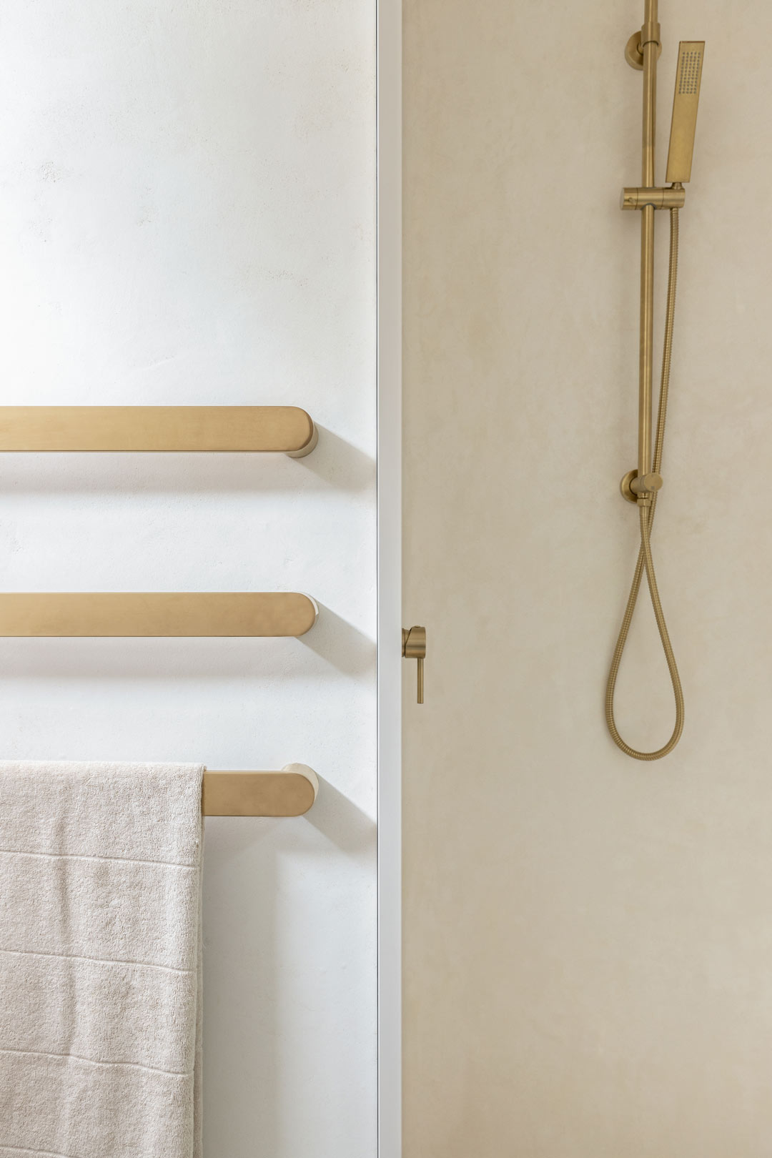 A-simple-mediterranean-style-bathroom-with-brushed-brass-tapware-shower-and-stacked-towel-rails