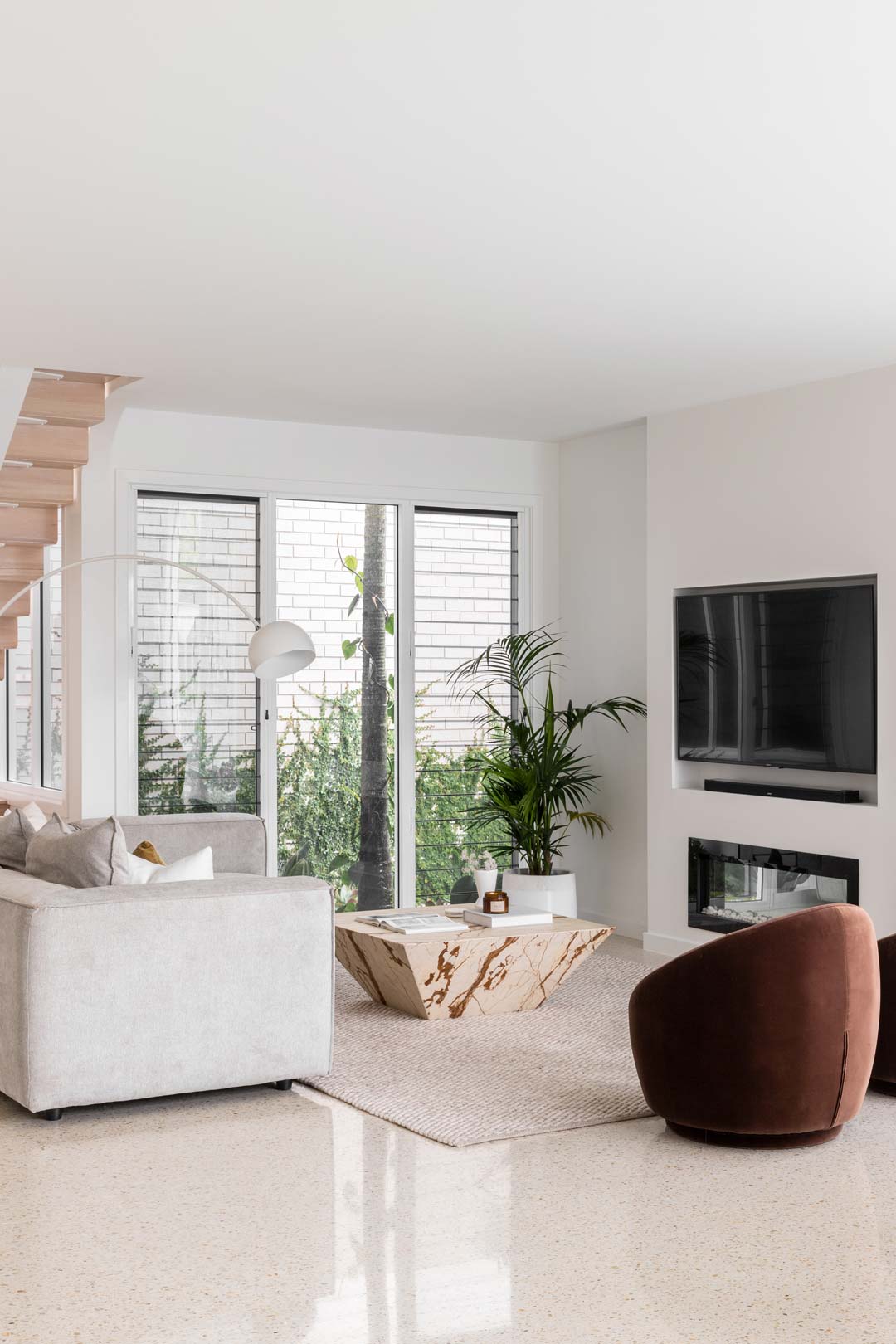 A-soft-neutral-living-room-in-a-renovated-queenslander-style-home-with-a-chocolate-brown-arm-chair-and-natural-stone-coffee-table