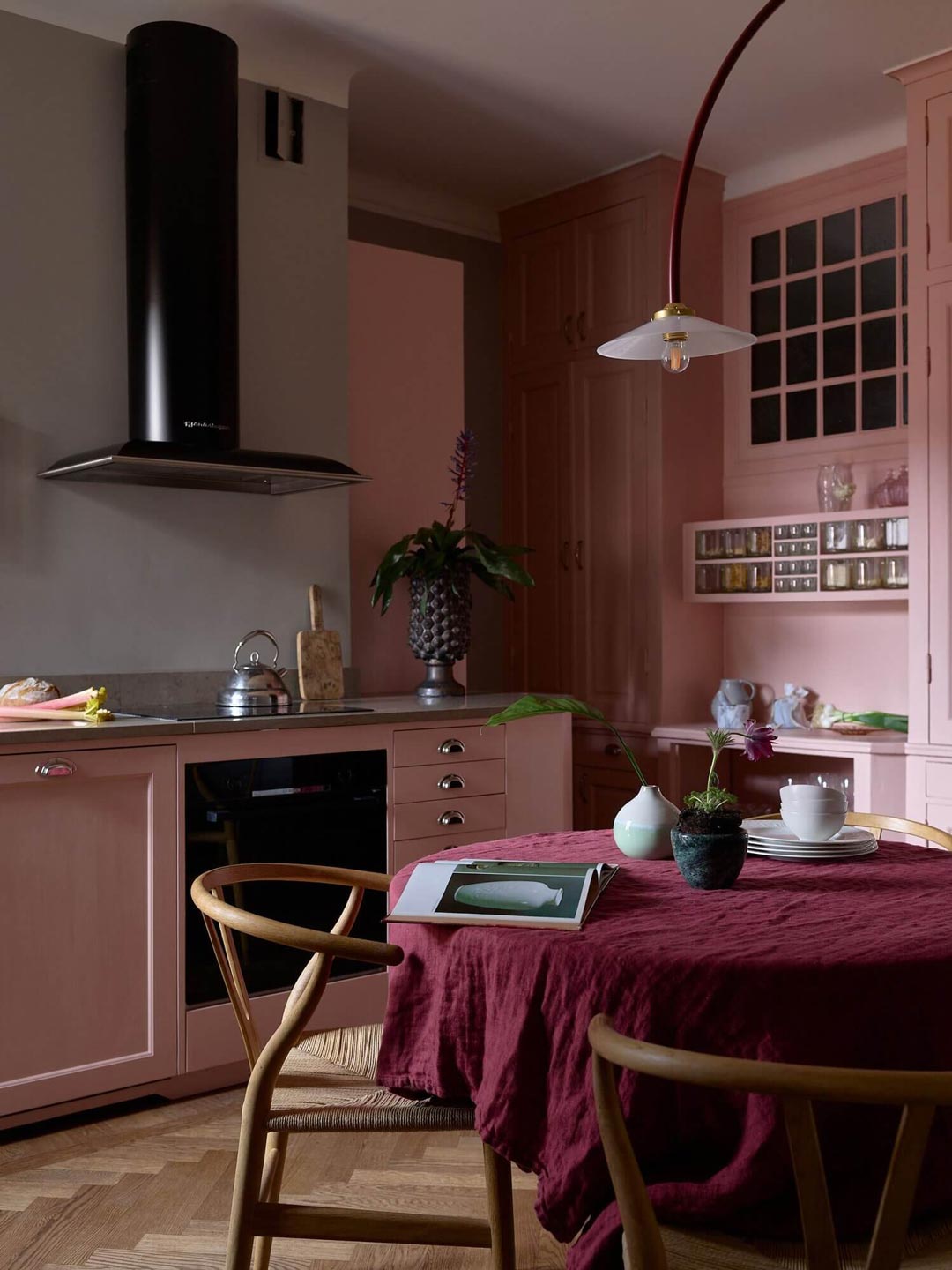 A-stunning-kitchen-with-muted-pink-cabinetry-and-a-magenta-table-cloth-complimented-with-timber-flooring