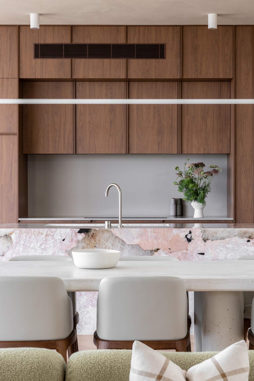 An-open-plan-kitchen-livin-and-dining-with-a-neutral-colour-palette-rich-warm-walnut-cabinetry-complimented-by-a-soft-green-boucle-couch-1
