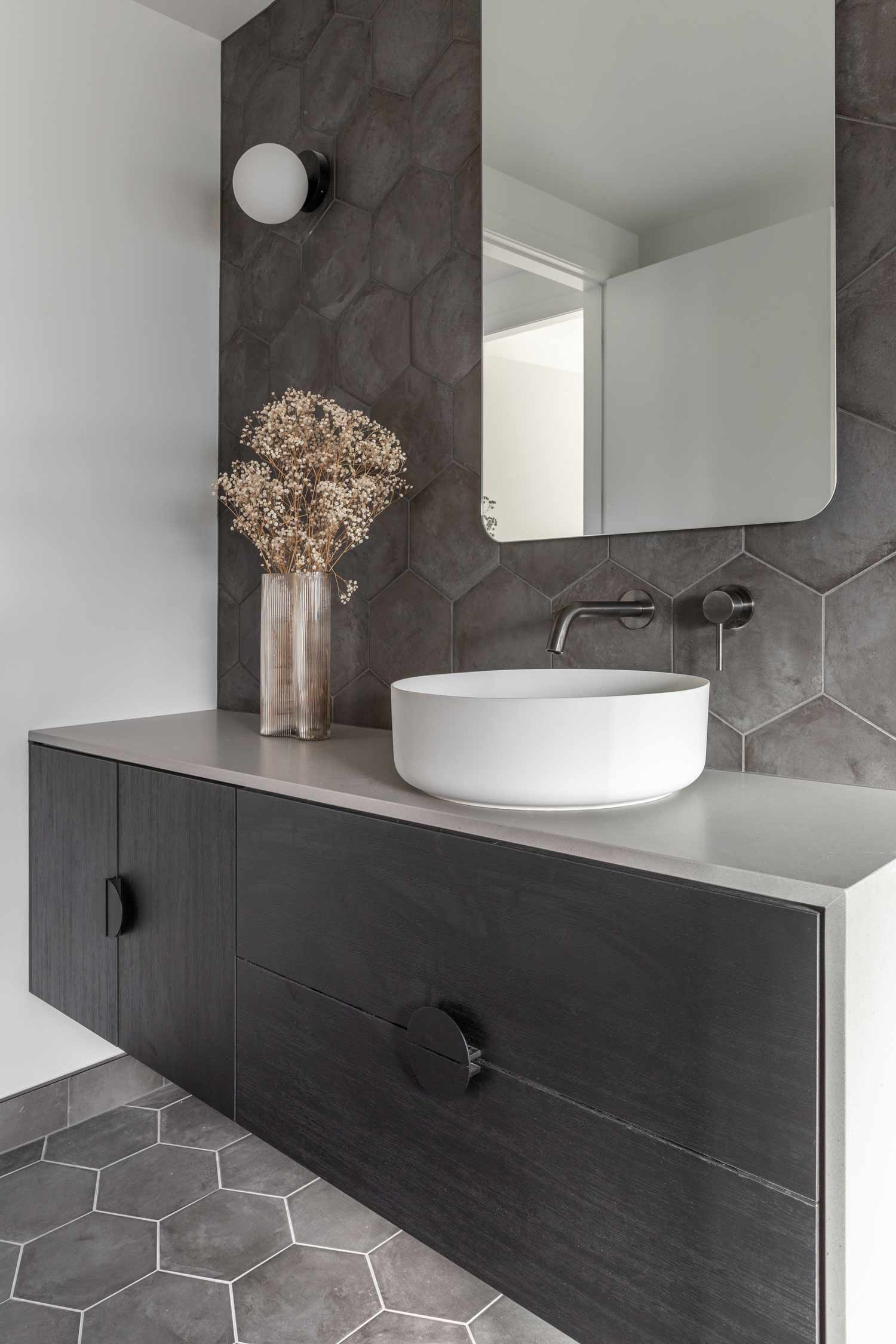 Dark-bathroom-ideas-for-an-industrial-house-include-a-dark-grey-feature-tile-gunmetal-grey-tapware-and-black-vanity-cabinet