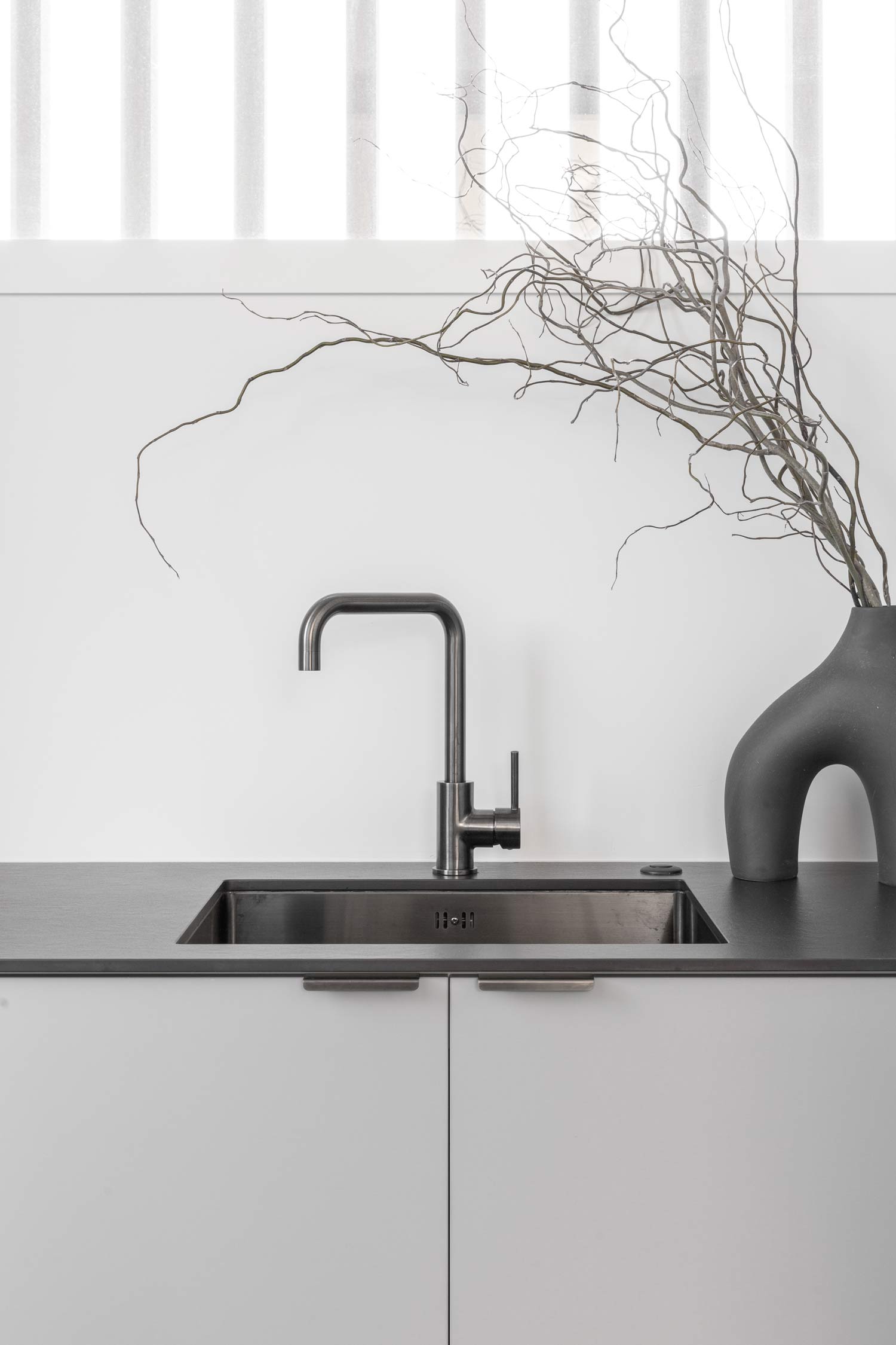 Light-grey-cabintry-dark-benchtop-gunmetal-sink-and-tapware-in-a-modern-contempory-industrial-laundry