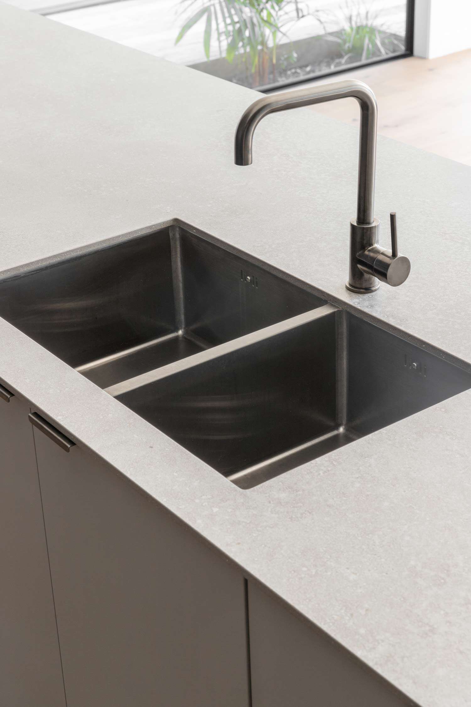 Light-stone-benchtop-gunmetal-sink-and-tapware-in-a-modern-industrial-kitchen