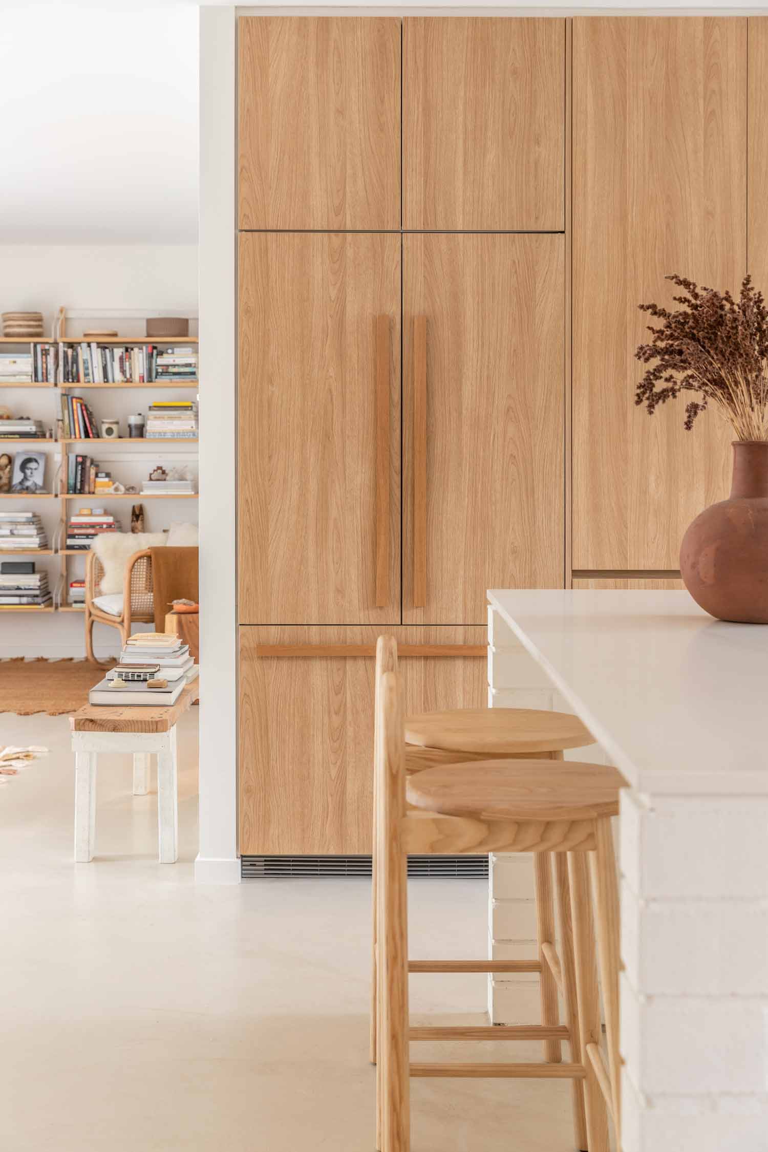Modern-coastal-open-plan-kitchen-and-living-with-warm-timber-cabinetry-soft-concrete-floors-and-a-study-book-nook