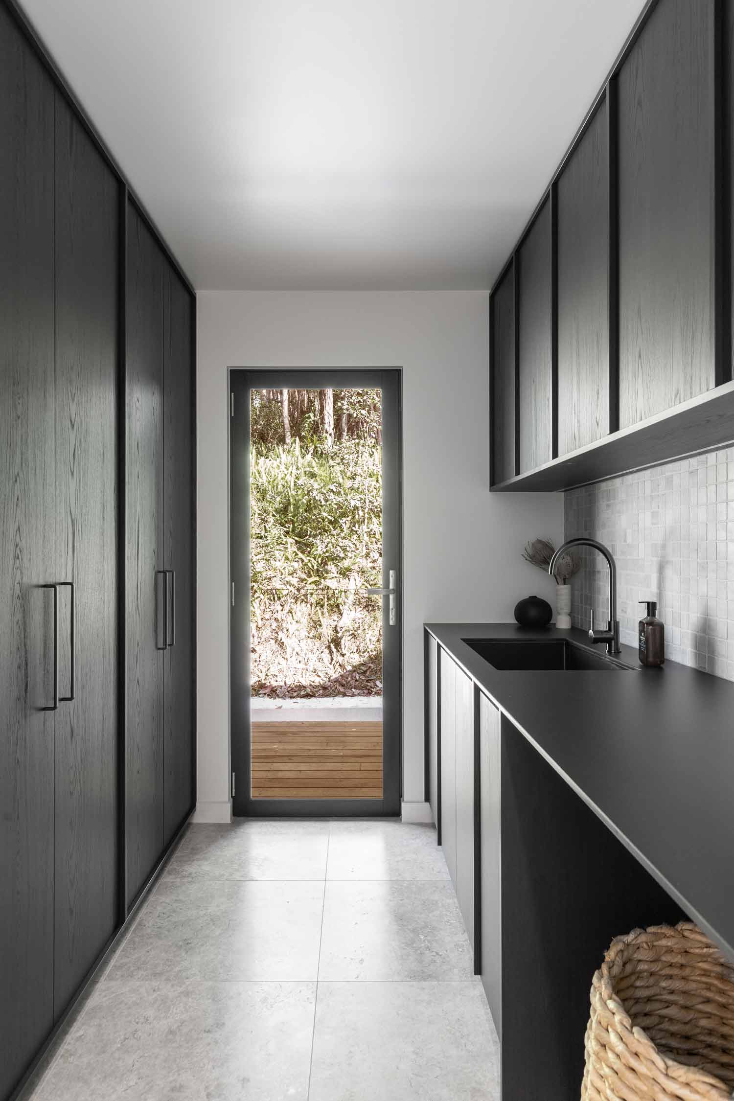 Monochomatic-interior-design-used-in-the-laundry-of-Kooringal-Lodge-dark-cabinetry-gunmetal-tapware-and-concrete-look-tiles