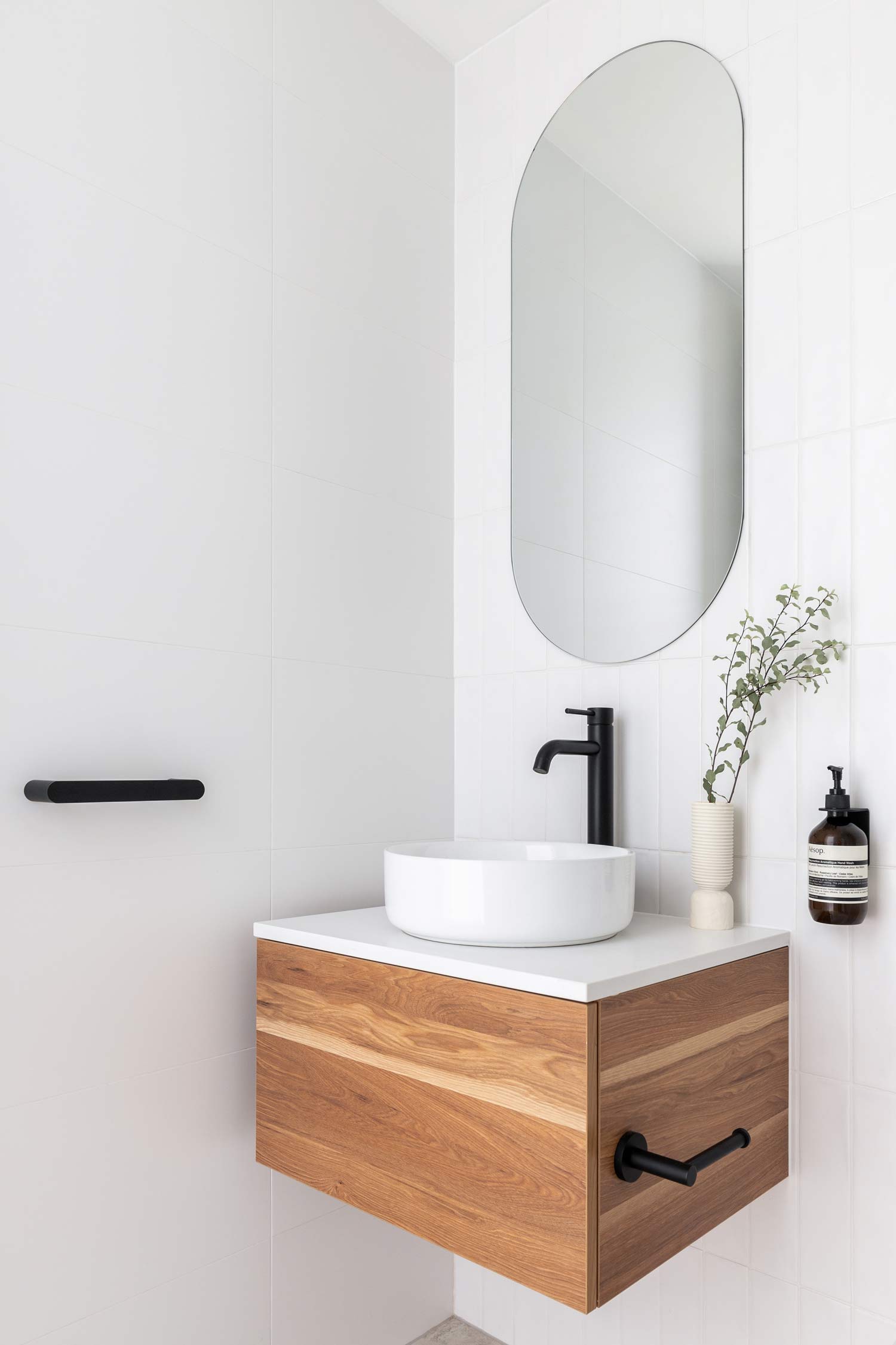 Simple-coastal-bathroom-design-with-matte-black-fixtures-white-soft-tiles-and-natural-timber-vanity