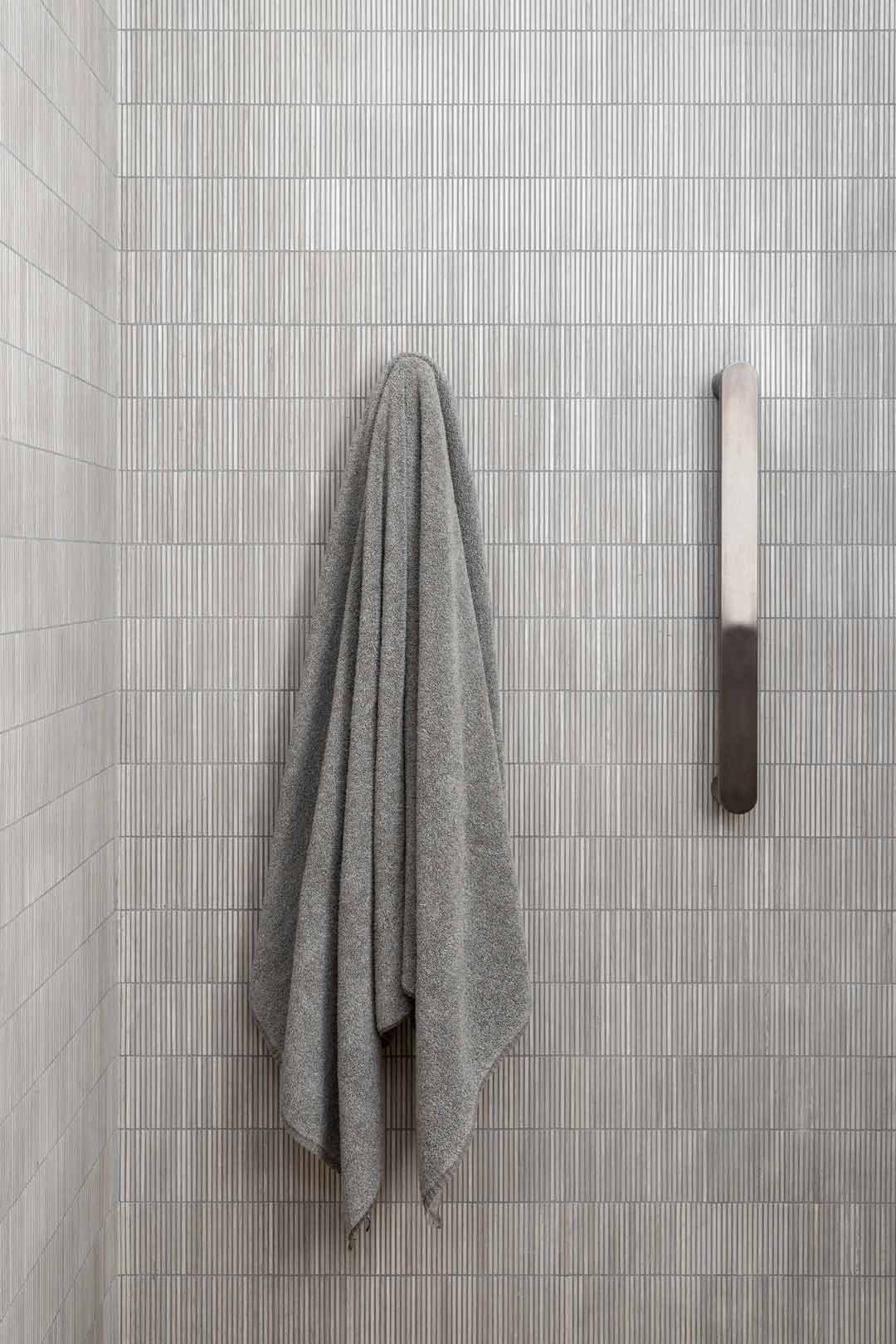 Travertine-slither-feature-tiles-paired-with-brushed-gunmetal-vertical-heated-towel-rails