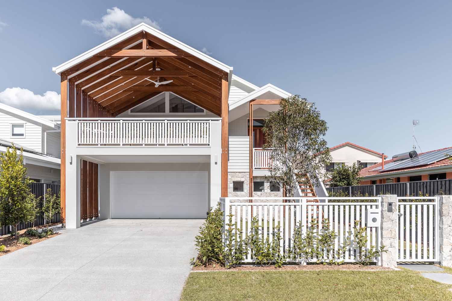White weatherboard coastal house with timber cladding and 4 car garage
