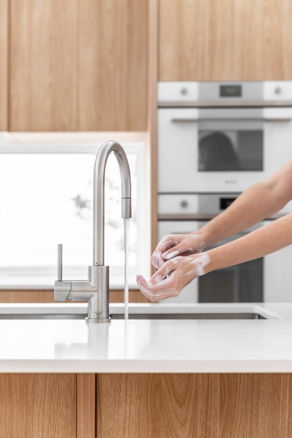 Woman-using-ABI-sensor-tap-in-kitchen-1024x1536-1